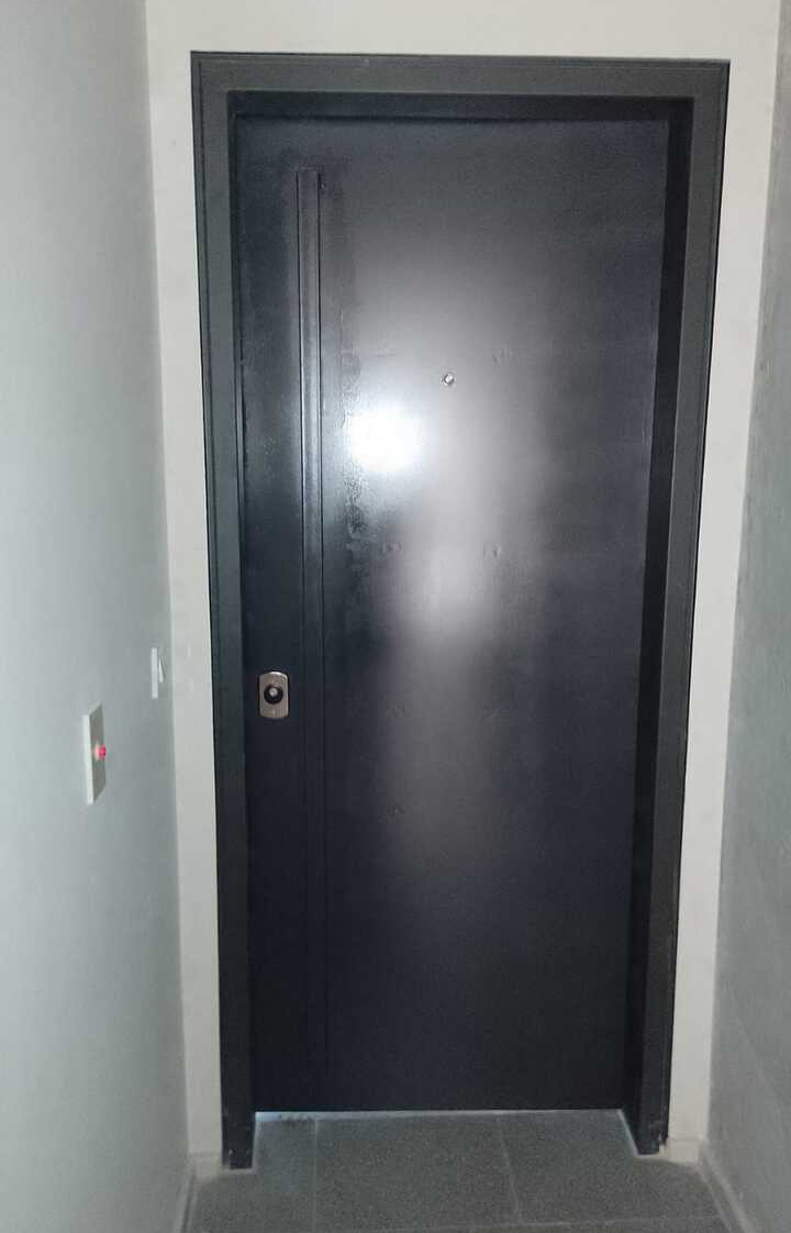 Blindaje de puerta lisa color gris grafito con herrajes plateados para departamento moderno