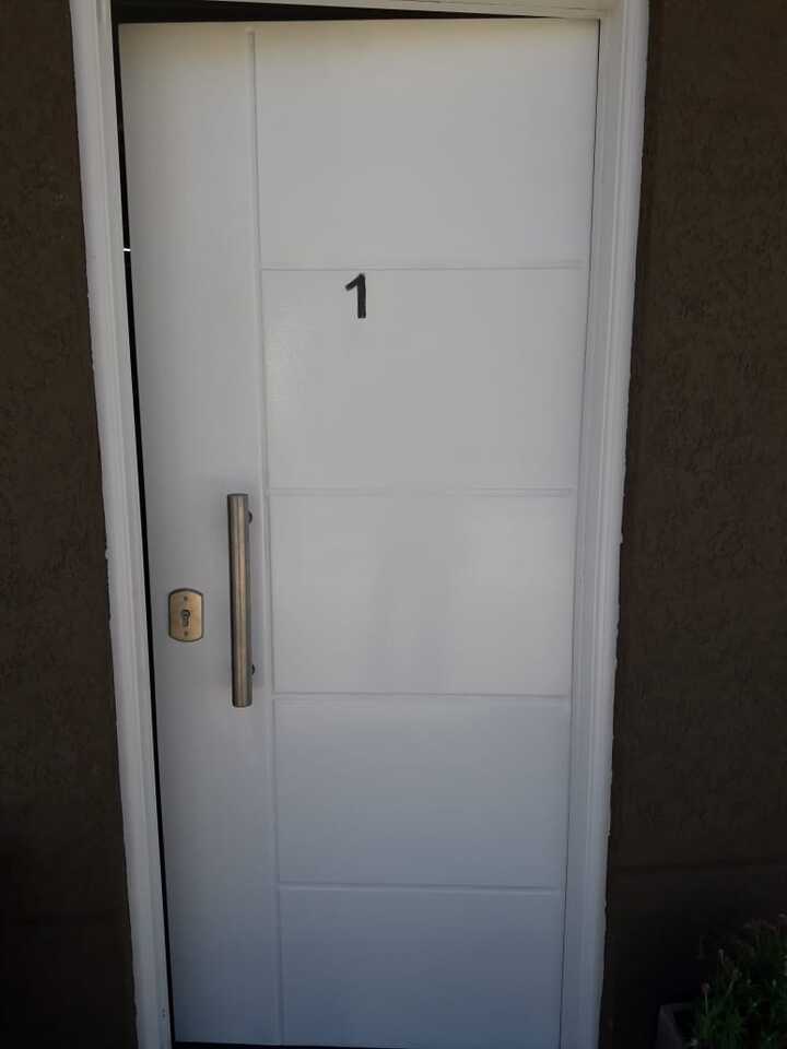 Puerta acorazada blanca con diseño de líneas y gran barral de acero inoxidable