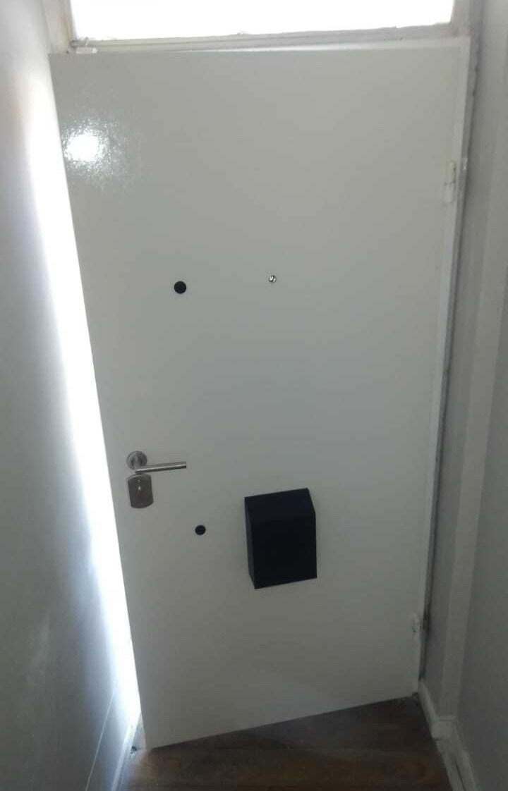 Puerta blindada blanca lisa con buzón negro instalada a medida y abierta