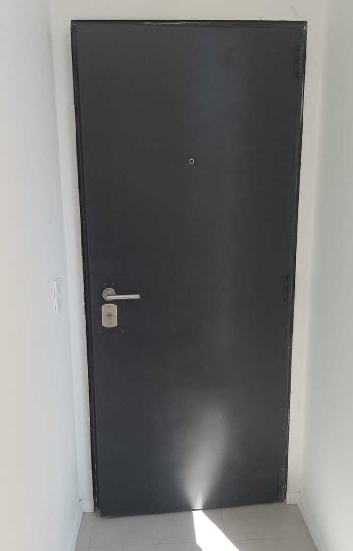 Puerta blindada simple color gris oscuro instalada a medida en pasillo interior