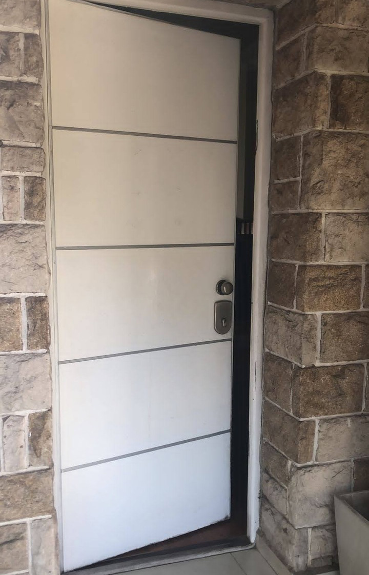 Puerta de seguridad blanca de diseño horizontal instalada en exterior de piedra